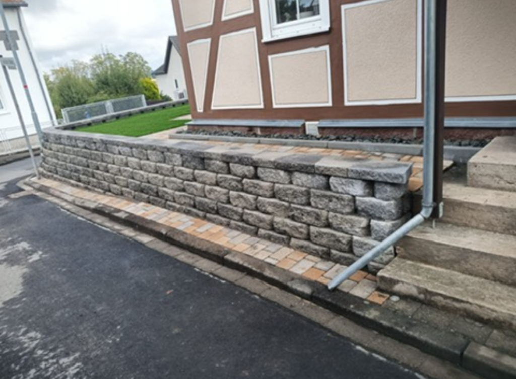 Fertige Mauer aus Betonsteinen entlang der Hauseinfahrt mit Treppenstufen